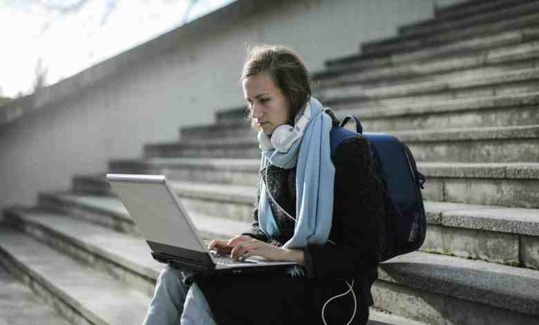 woman sitting on concrete stairs using laptop