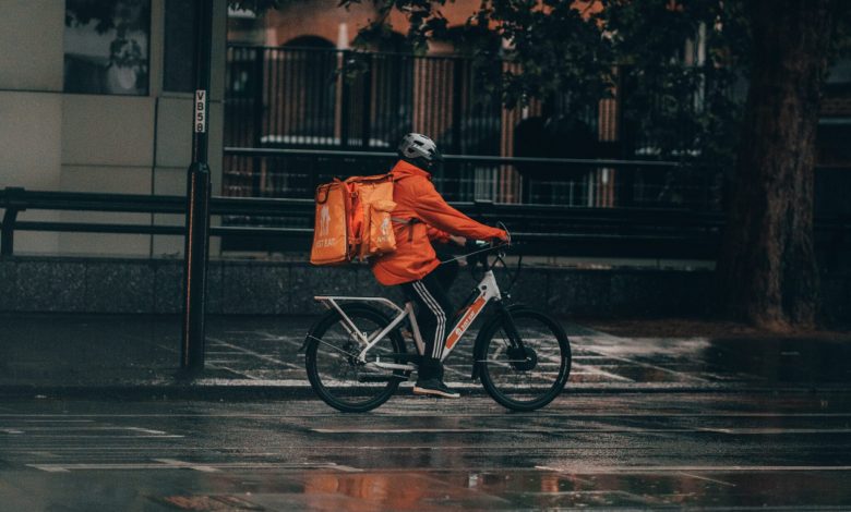 man in orange jacket riding bicycle on street during nighttime