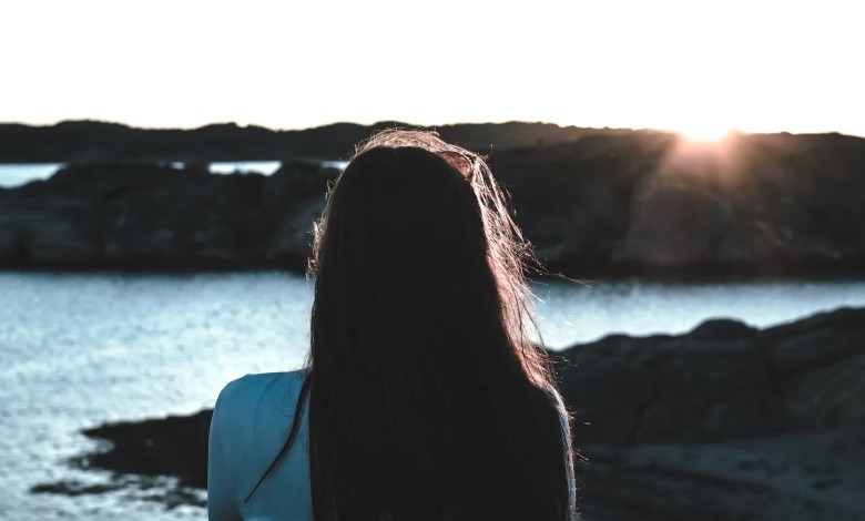 photo of woman in white shirt near body of water