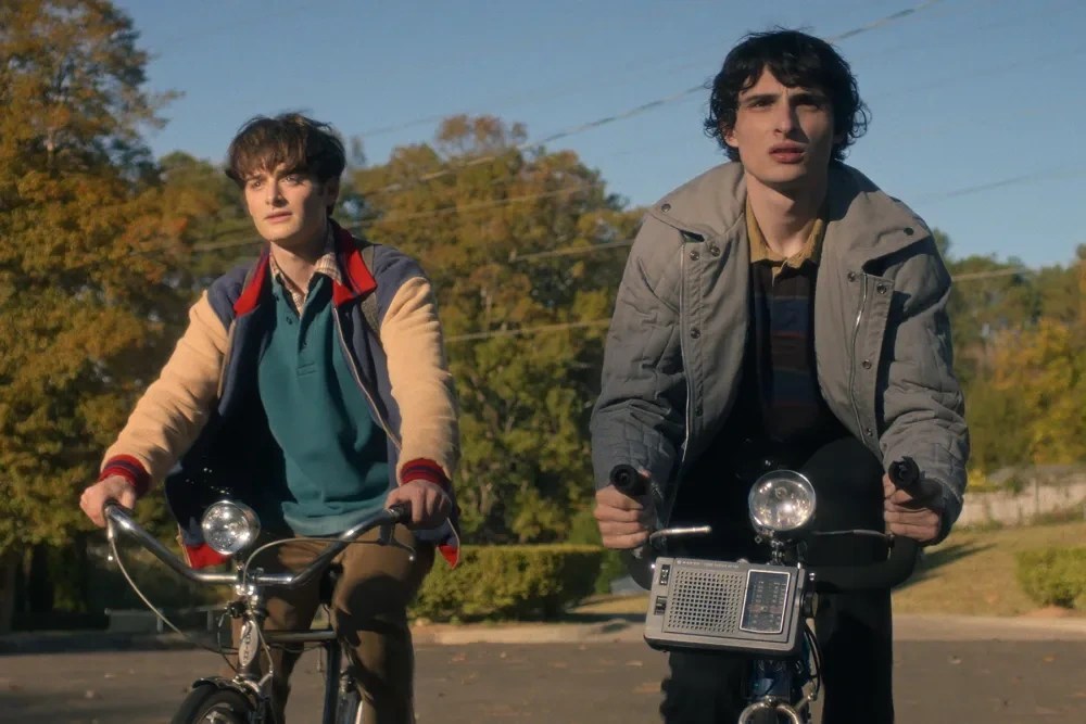 Will Byers and Mike Wheeler riding bicycles in Stranger Things Season 5, showcasing production design and period-accurate costumes.