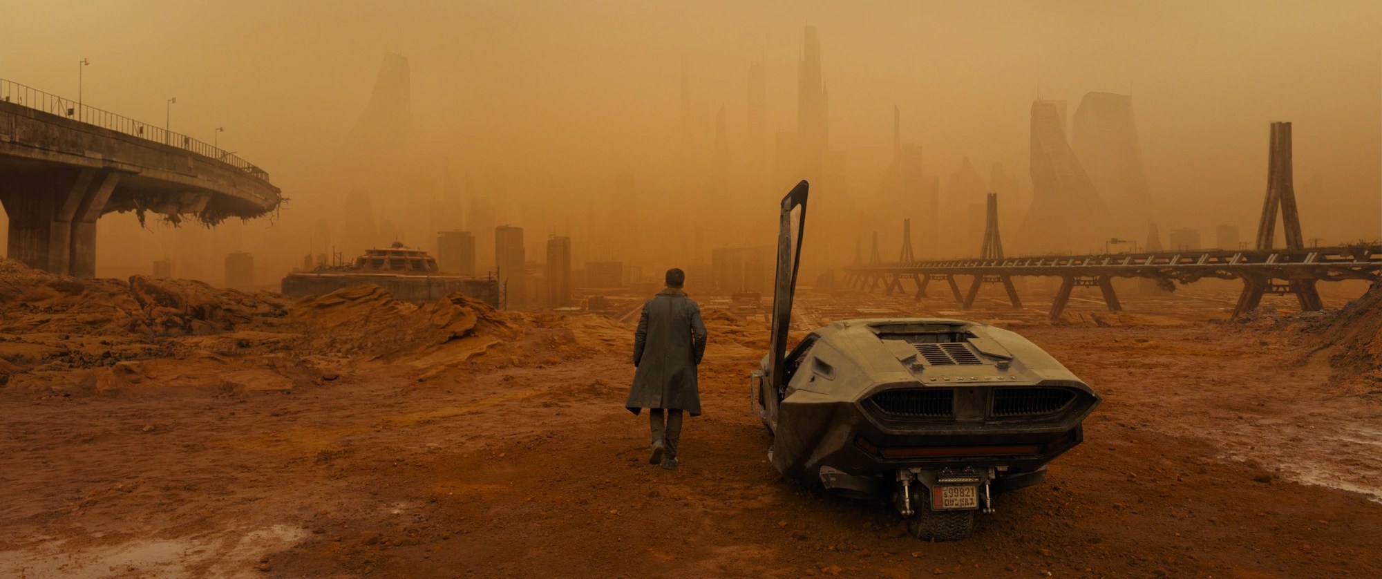 Officer K walking through a radioactive orange dust storm in Las Vegas in Blade Runner 2049, highlighting the use of monochromatic orange color palettes.