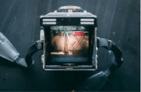 A close-up top view looking into a film camera viewfinder showing a scene being framed on a set.