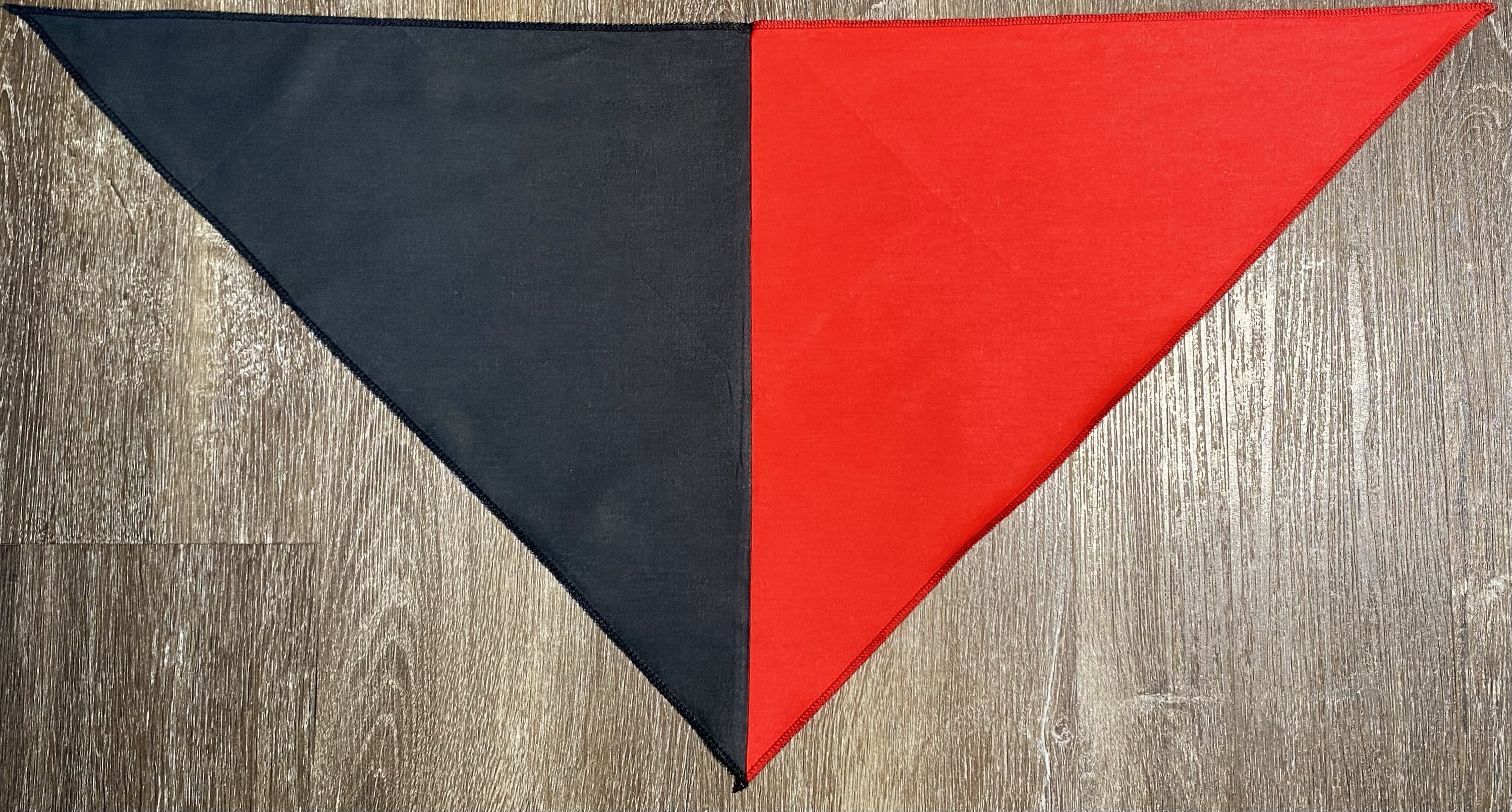 Red and black triangular revolutionary neckerchief laid flat showing half\-red half\-black design and finished edges