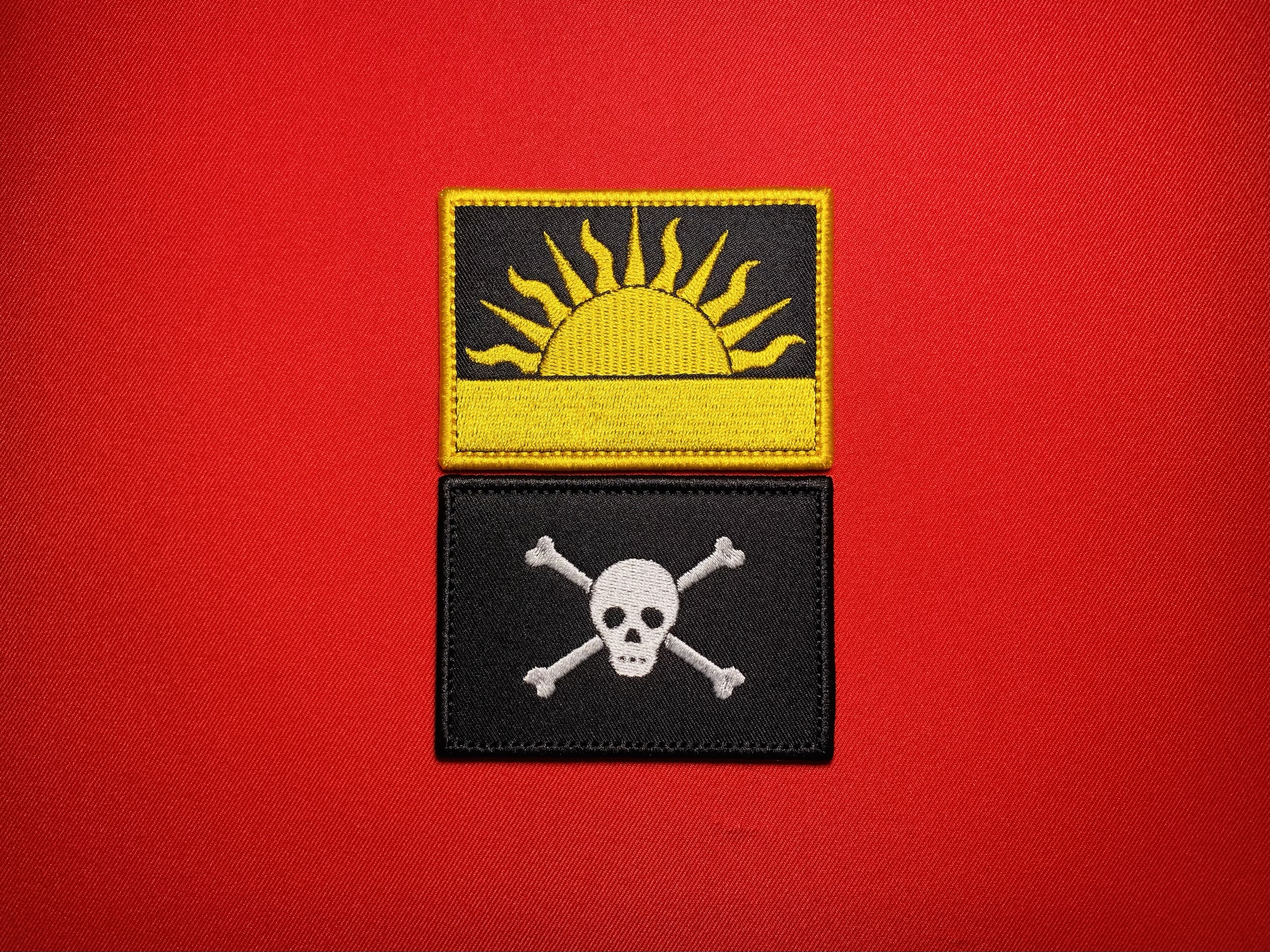 Two embroidered Biafran historical reproduction patches featuring the yellow Rising Sun insignia and the white skull and crossbones emblem associated with Rolf Steiner’s 4th Commando Brigade during the Nigerian Civil War.