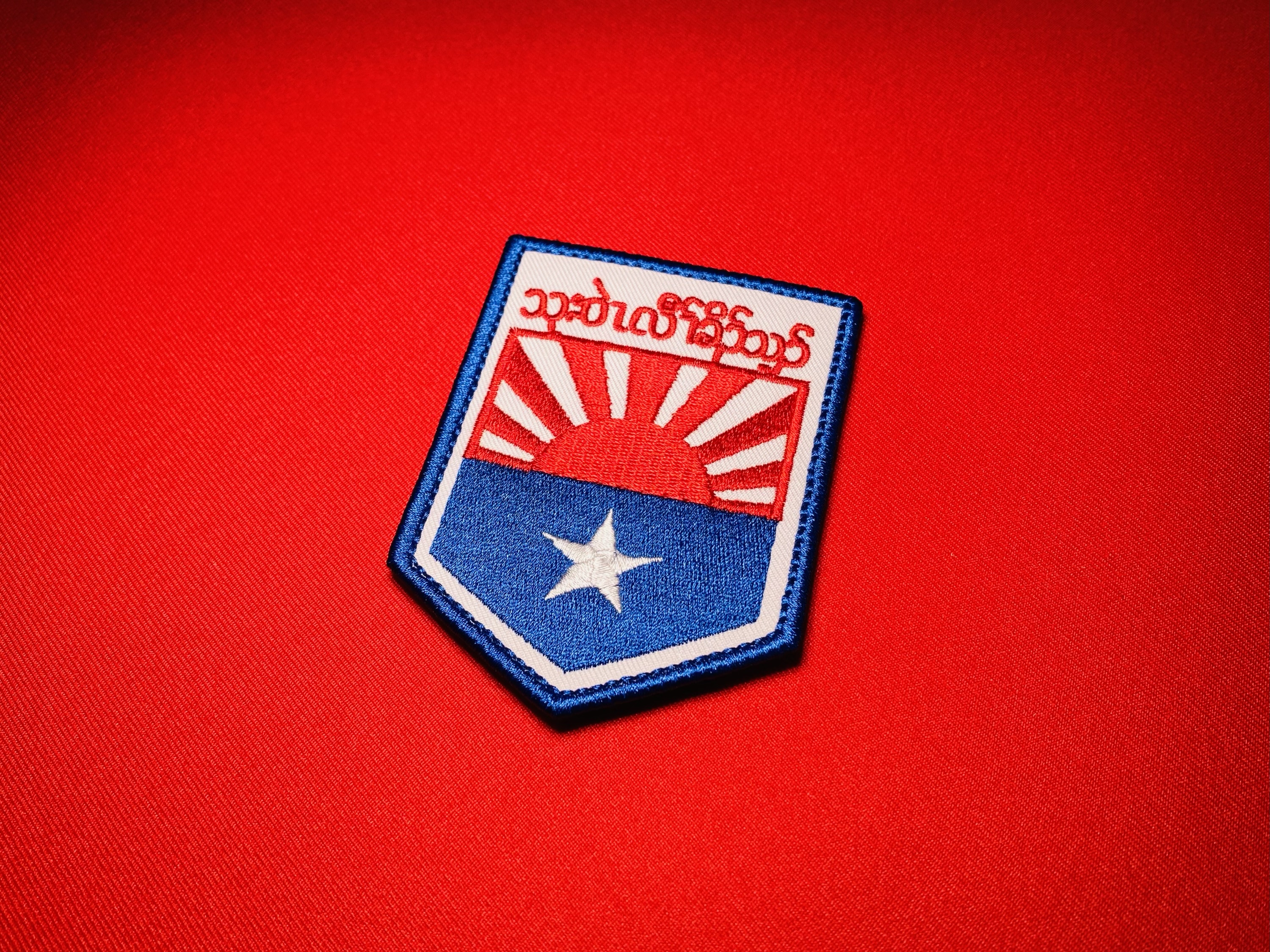Karen National Liberation Army KNLA Military Headquarters embroidered patch shown at an angle, featuring S’gaw Karen text, a red rising sun, blue field, and white star.