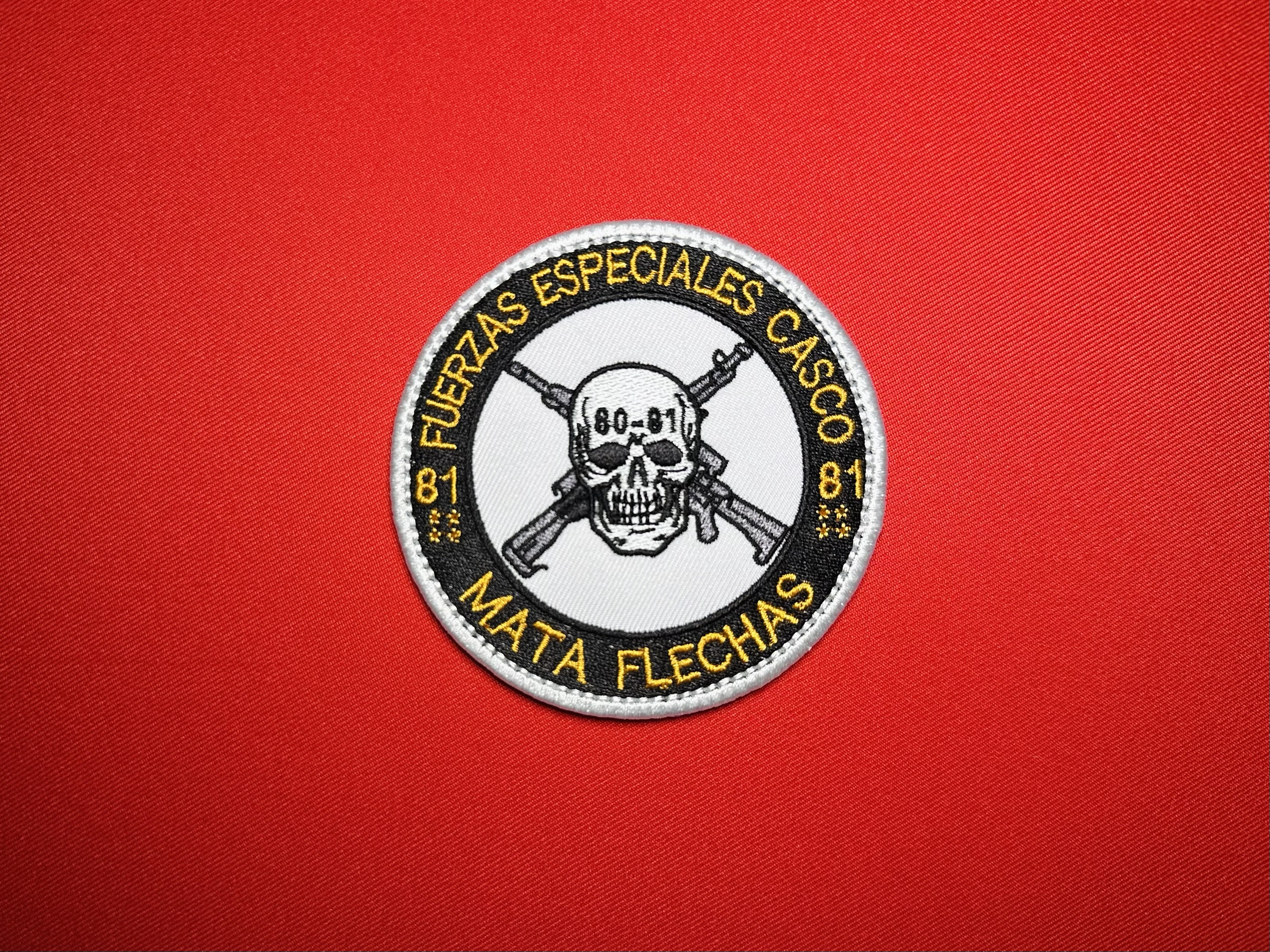 Los Chapitos Mata Flechas embroidered reproduction patch featuring Fuerzas Especiales Casco lettering, an 80-81 skull, crossed rifles, and a white border on red fabric.
