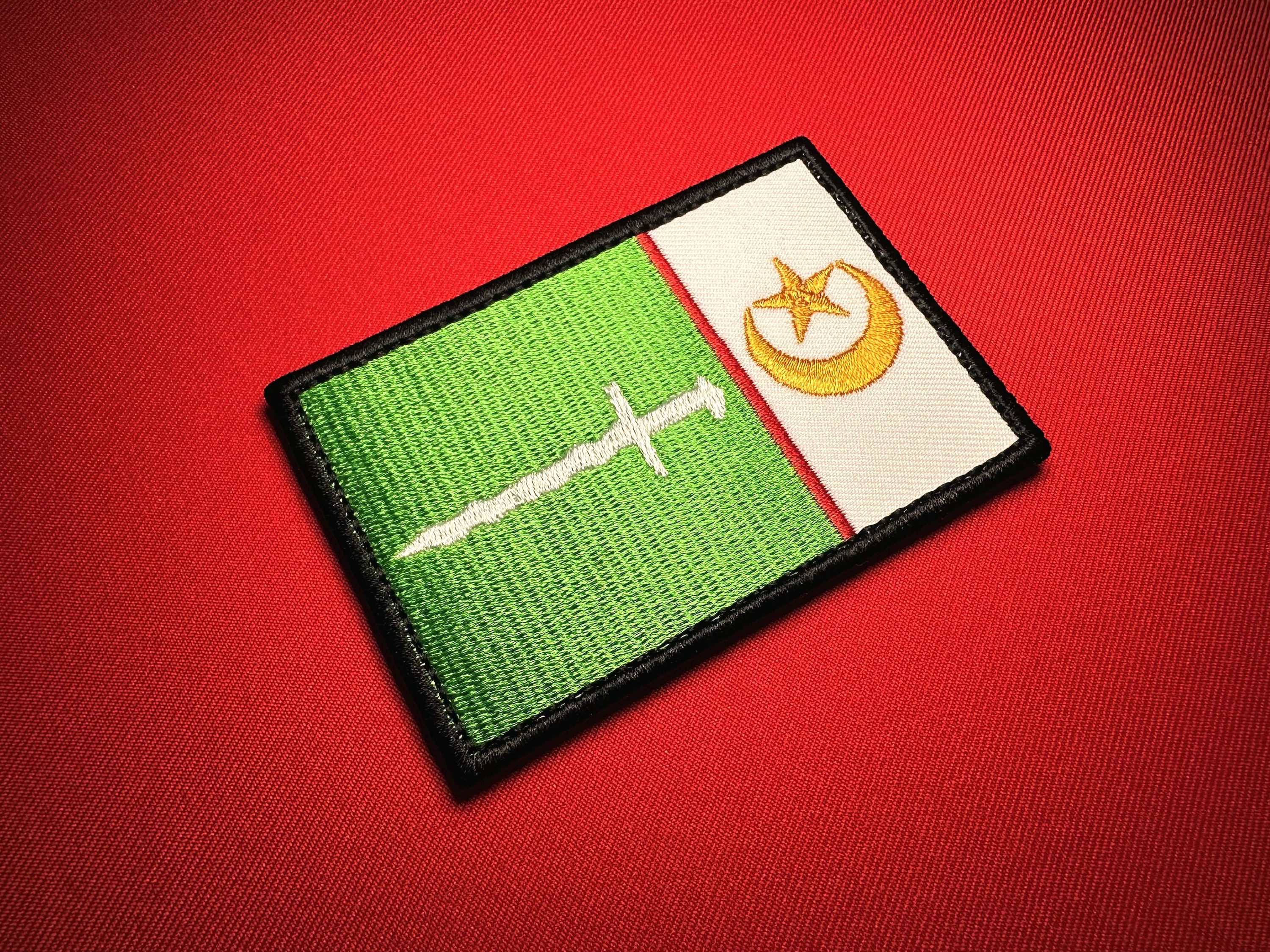 Angled close-up of a Moro Islamic Liberation Front (MILF) reproduction embroidered flag patch, featuring a white sword on green, gold crescent and star on white, red divider, and black satin border.
