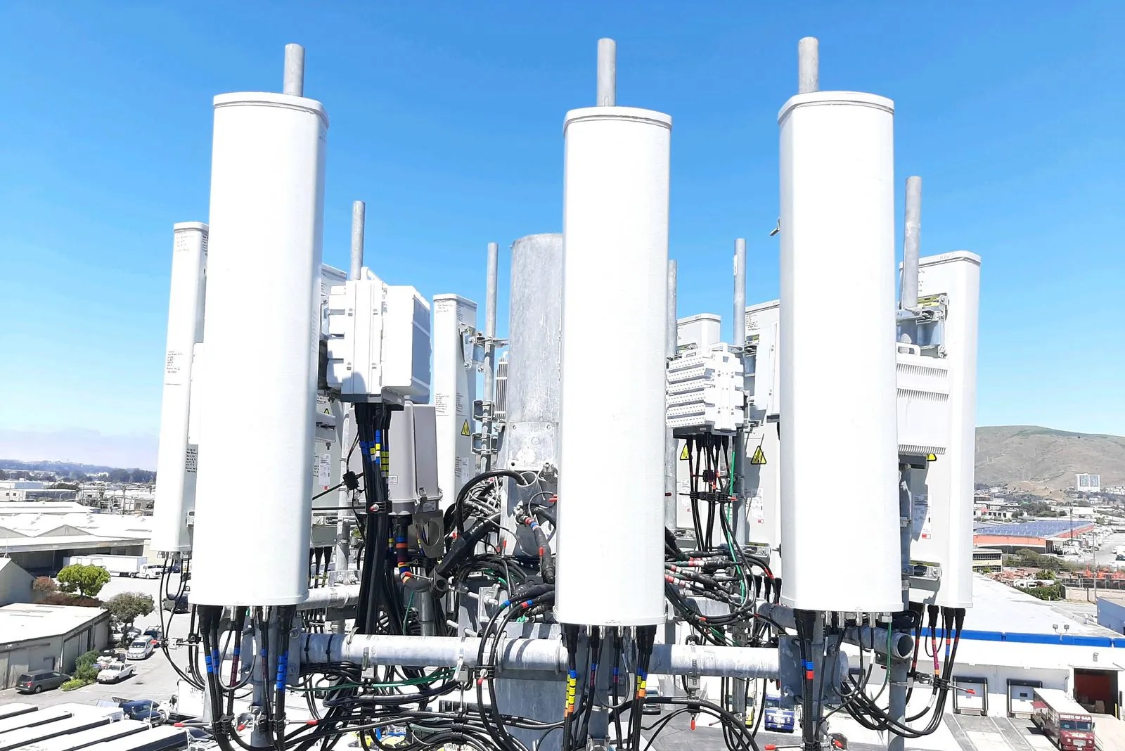 Rooftop installation of tall white antenna enclosures with radios and cabling