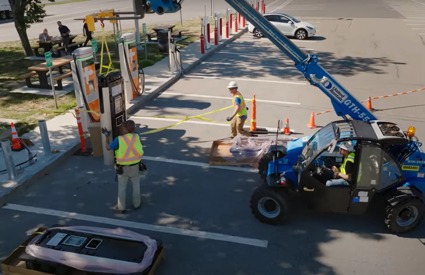 3S Network crew in hard hats and high-visibility vests on a coned-off installation site, with a telehandler lifting equipment