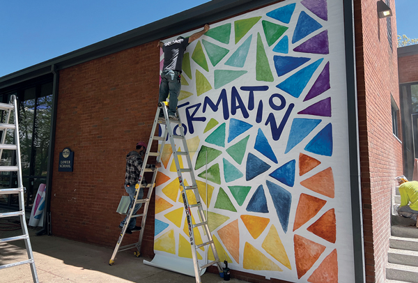Installer holding up panel of large brick wall mural