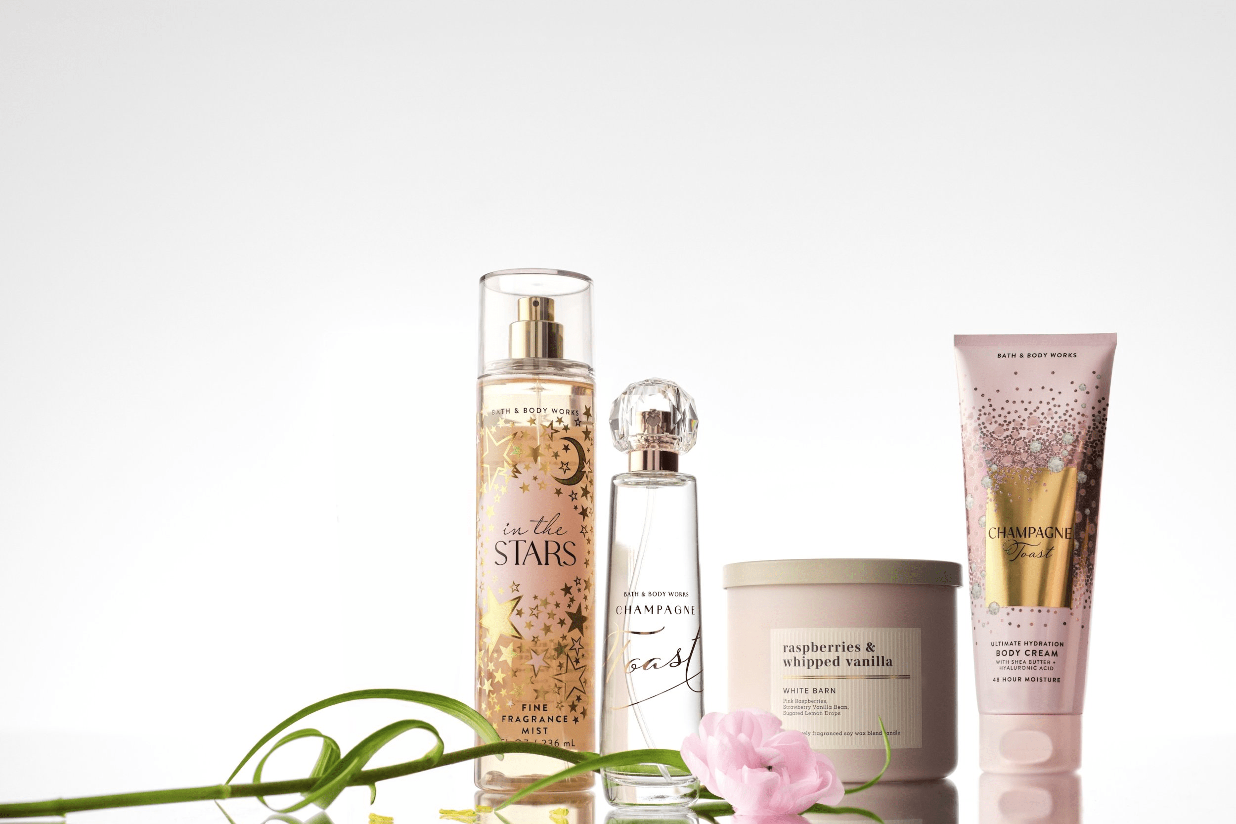 Bath and Body Works In the Stars fine fragrance mist Champagne Toast eau de parfum White Barn candle and body cream products styled with a pink flower and green stems