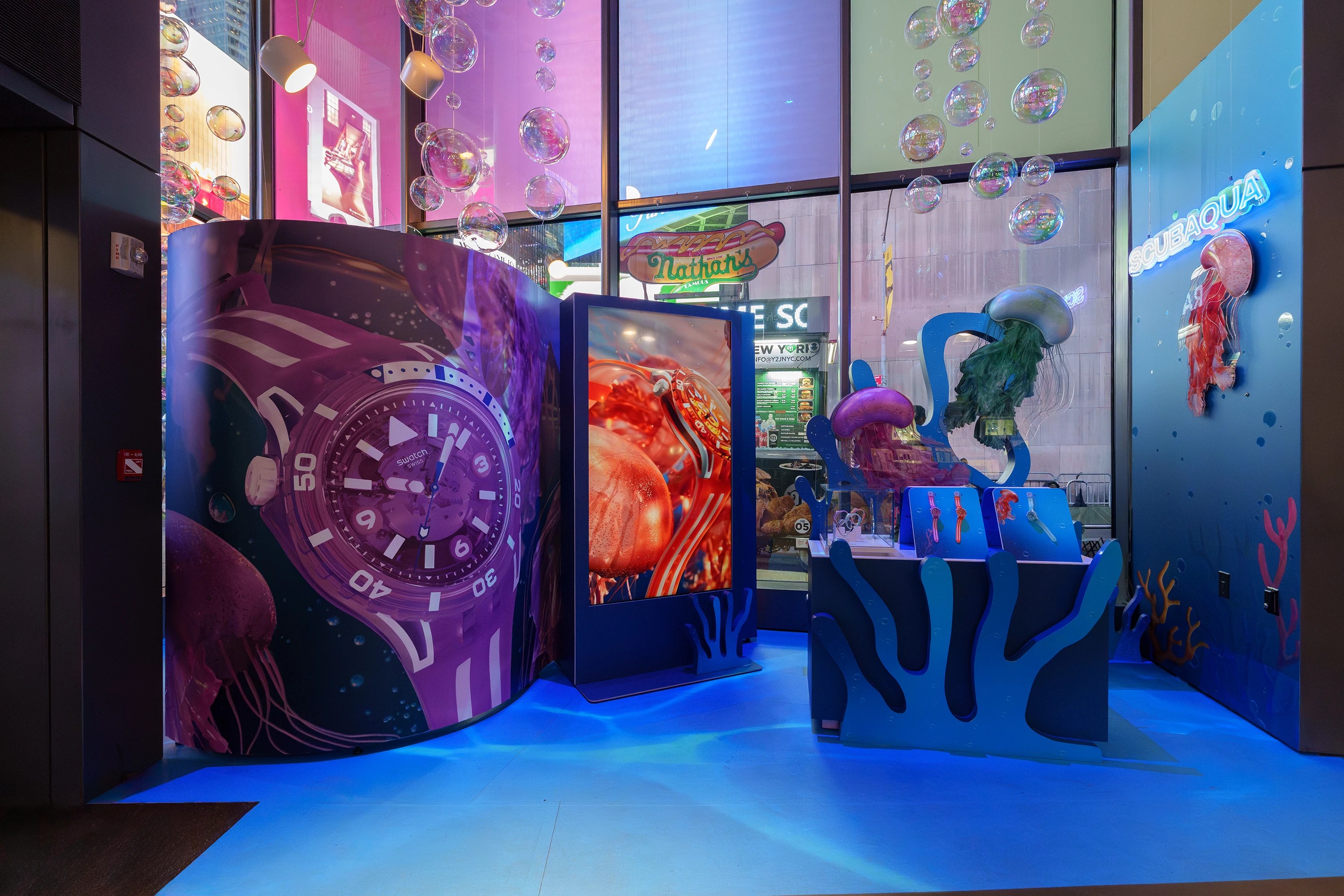 Swatch Scubaqua Times Square store with curved large-format print wrap, digital display screen, neon signage, and suspended bubble ceiling installation