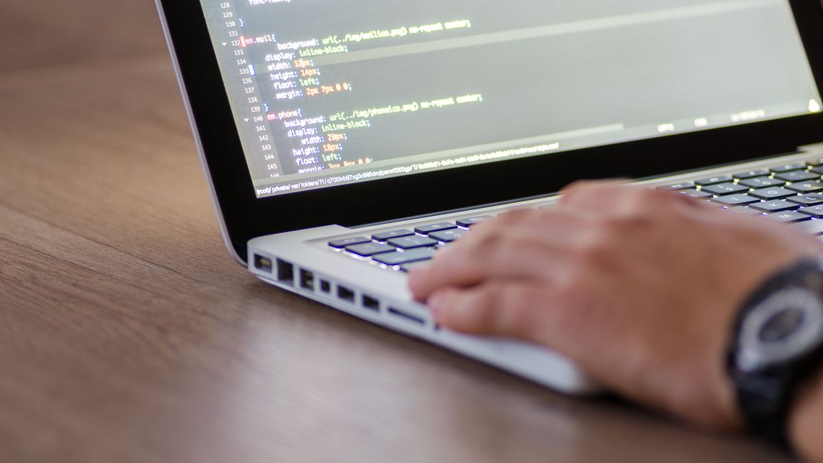 Person coding on a laptop with HTML code on screen, showcasing development work.