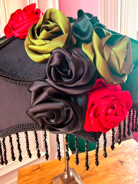 A close up of satin flowers on a black and greed lampshade