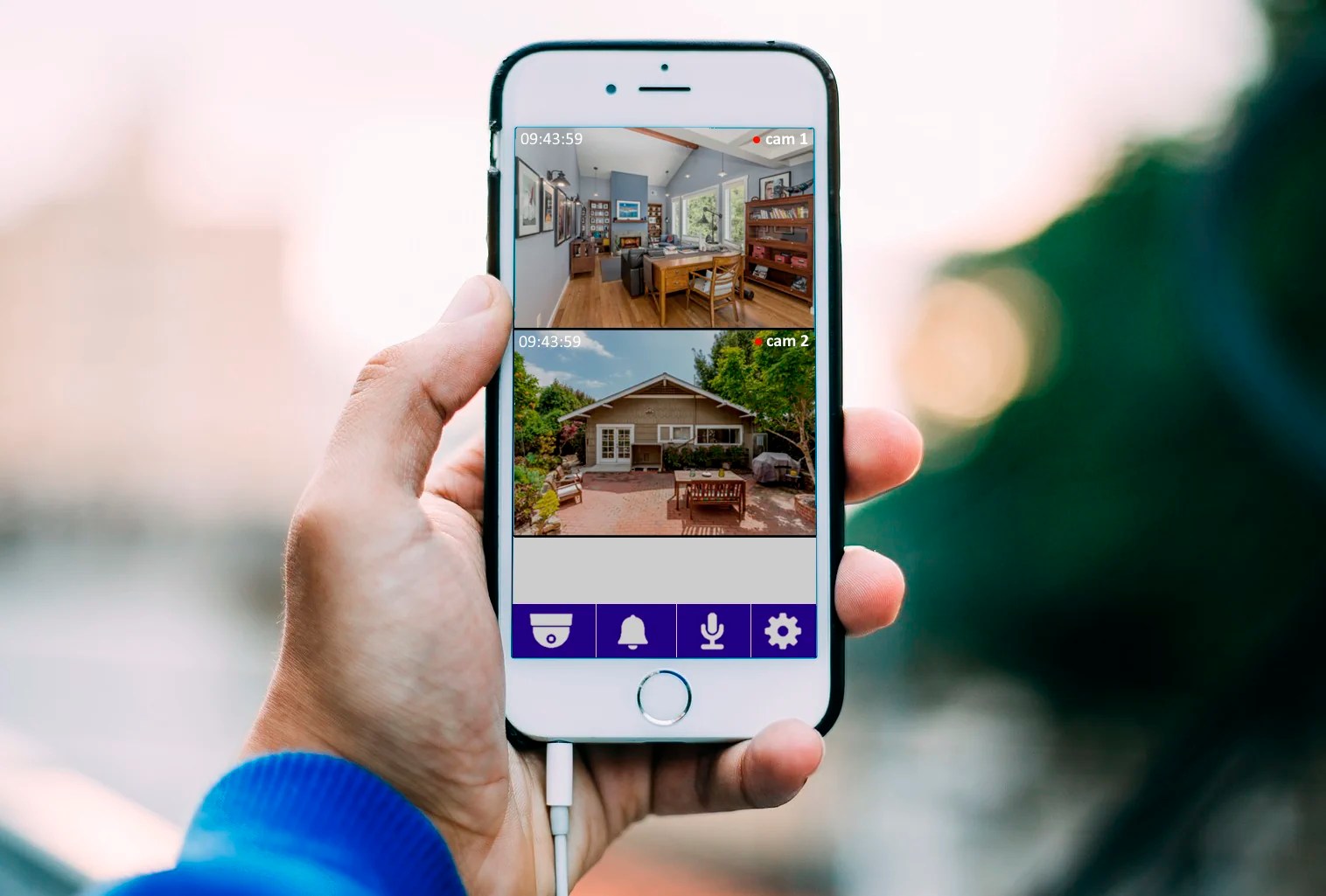 hand holding smartphone showing two remote security camera feeds from home security cameras on a residential property