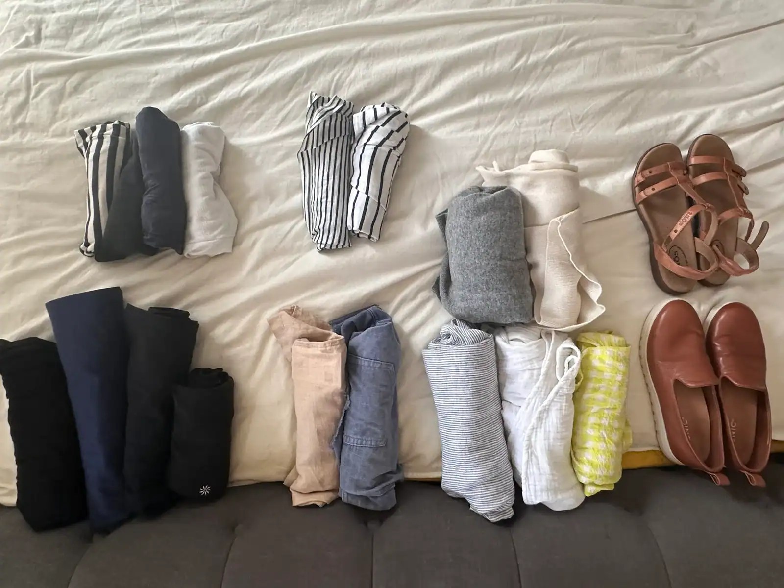 Clothing set out on a bed in a minimal color palette in order to prepare for a year abroad