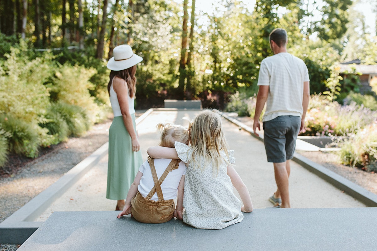 Photo of a family playing bocce ball in their backyard and two little girls are hugging