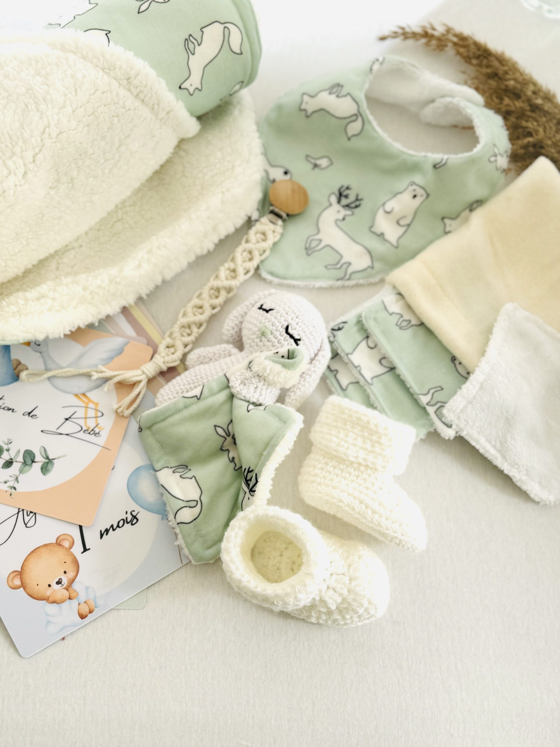 Coffret naissance polaire fait main, aux tons doux et hivernaux. Un cadeau artisanal complet avec doudou, couverture, lingettes, chaussons et cartes étapes.