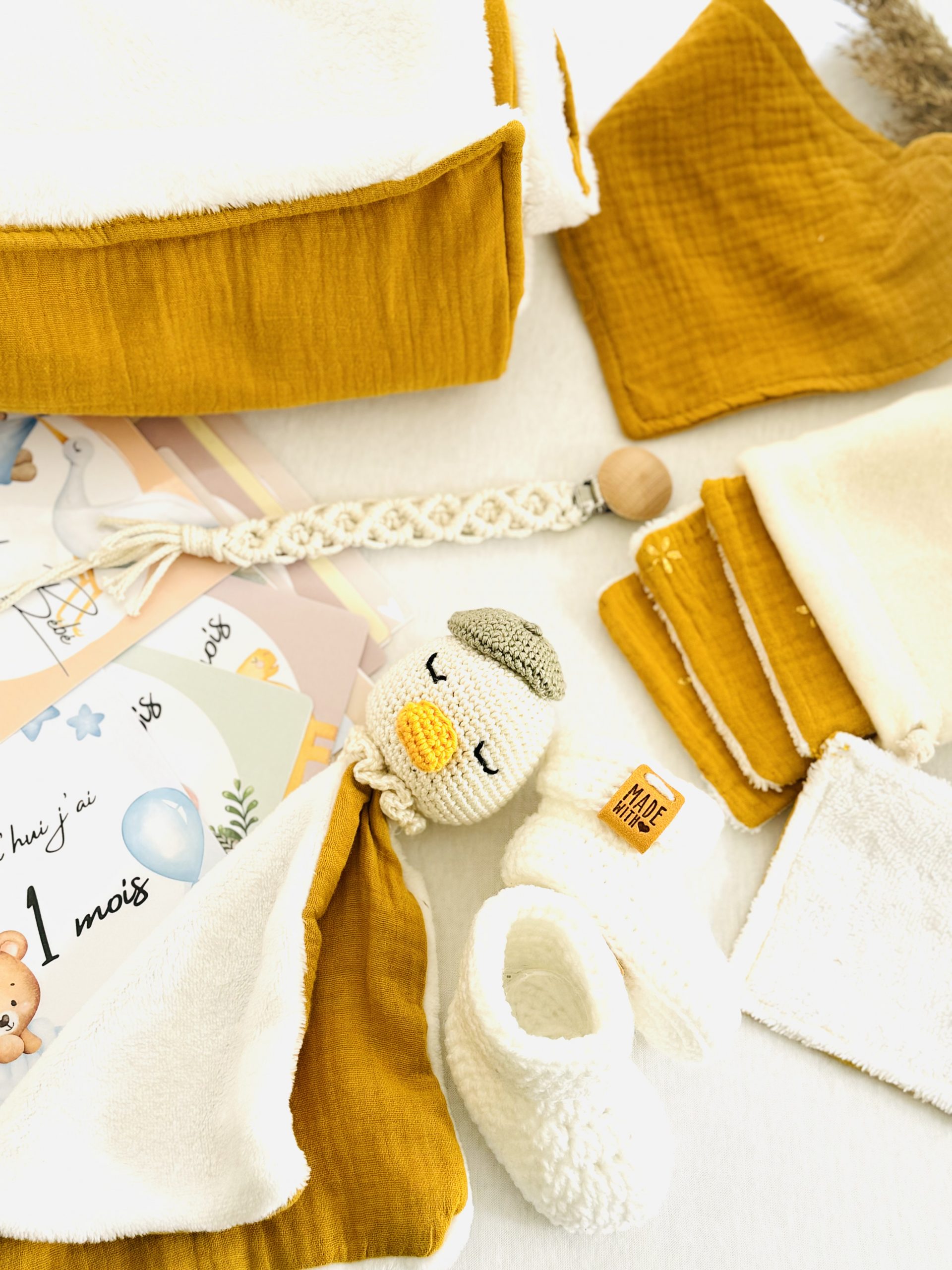 Coffret naissance soleil fait main, lumineux et artisanal. Contient doudou, couverture, lingettes, chaussons, bavoir, attache-tétine et cartes étapes.
