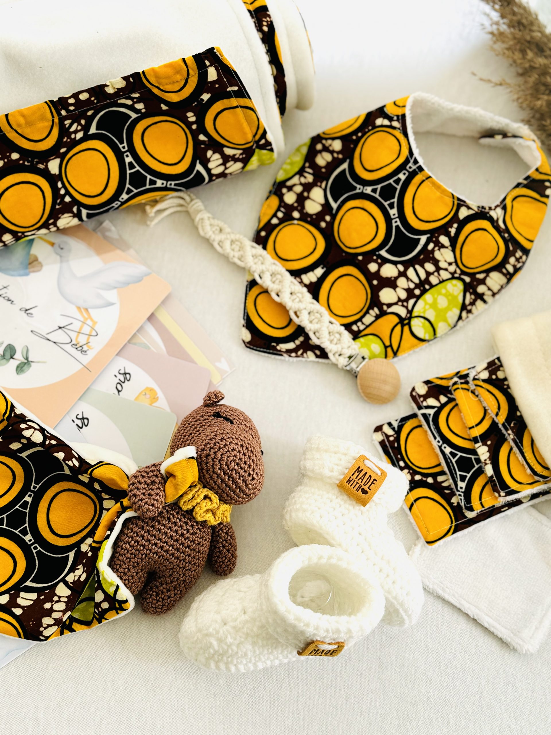 Coffret naissance safari wax : cadeau artisanal et coloré pour bébé, avec couverture, doudou, chaussons, lingettes, bavoir, attache-tétine et cartes étapes.