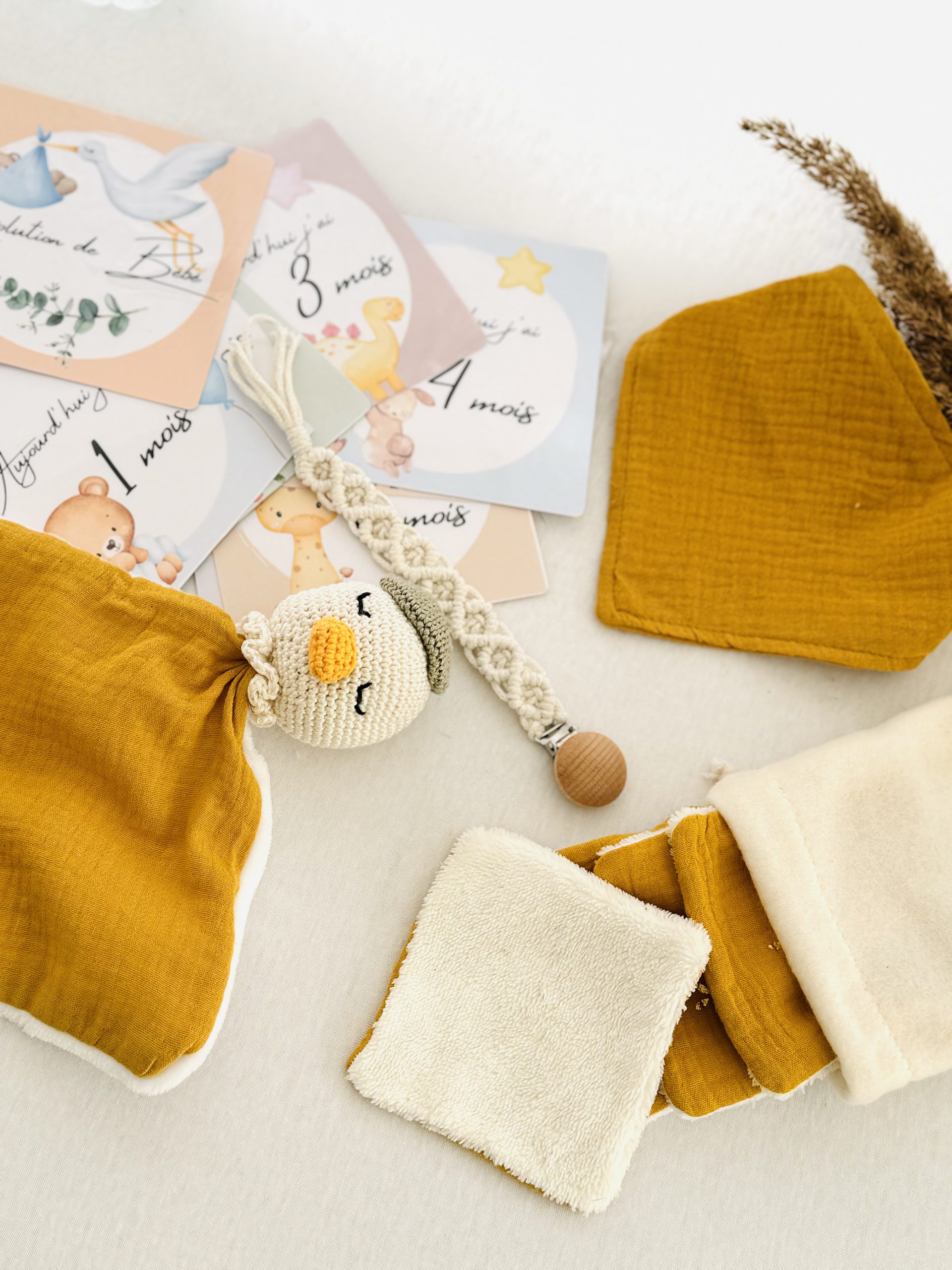 Coffret naissance Rayon de Soleil fait main, composé d’un doudou, bavoir, lingettes, attache-tétine et cartes étapes. Un cadeau artisanal et lumineux.