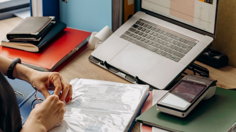 Professional organizing important documents in binders at a modern office desk.