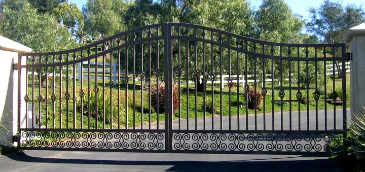 Black arched ornamental iron double driveway gate with scrollwork at the base