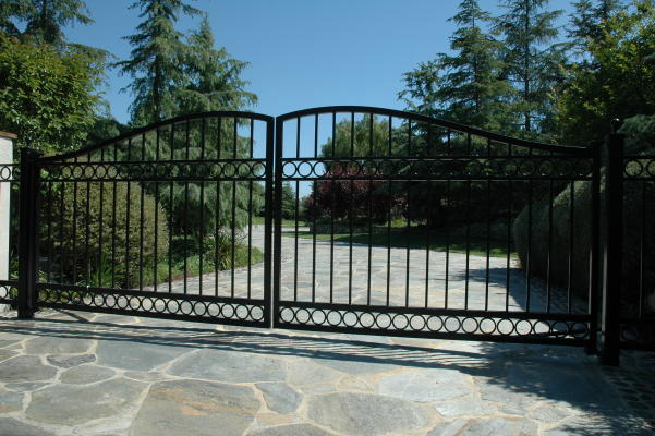 Black arched double driveway gate with circular iron details and scrollwork