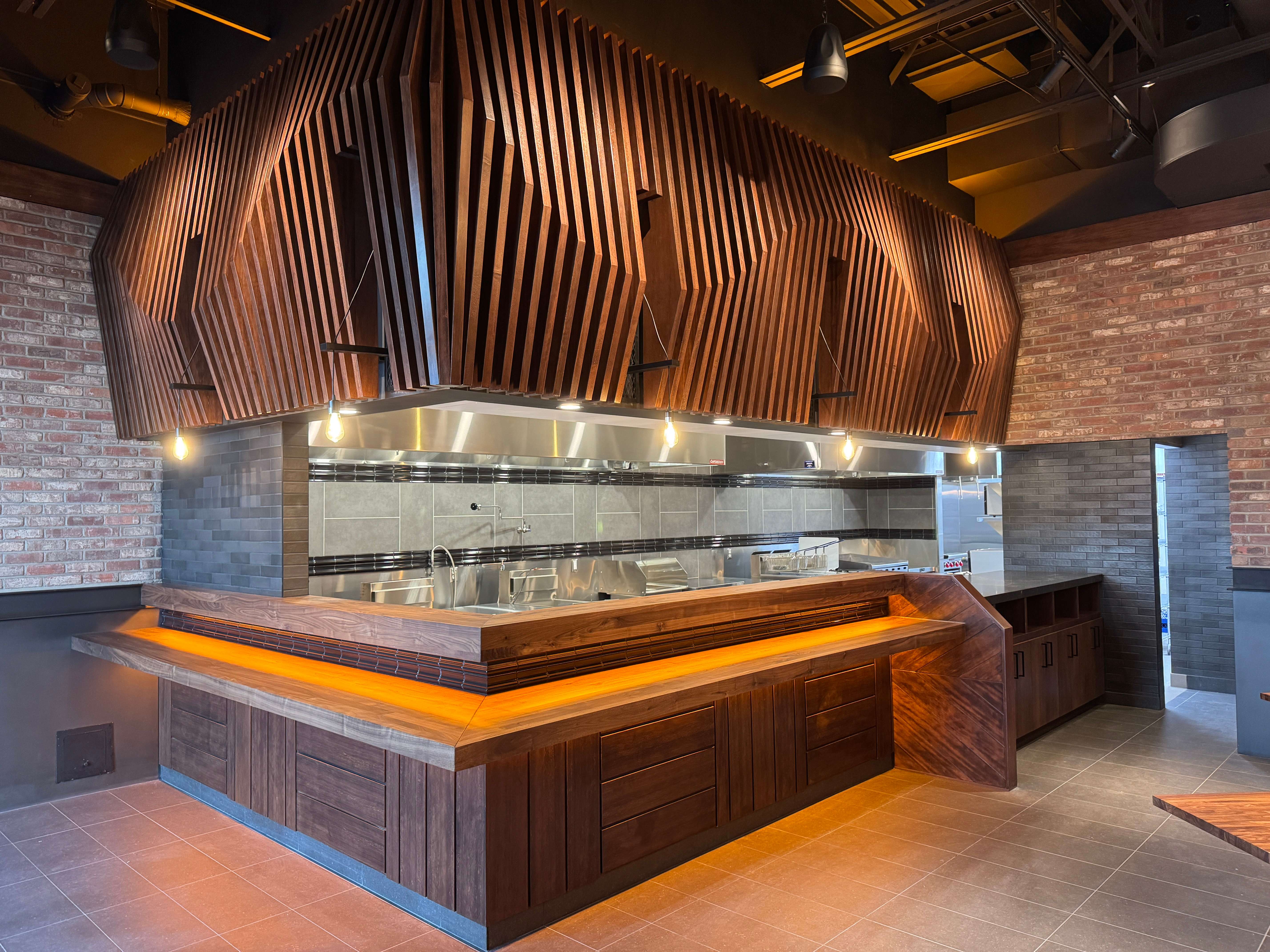 Open kitchen with sculptural wood slat millwork at JINYA Ramen Bar Macleod