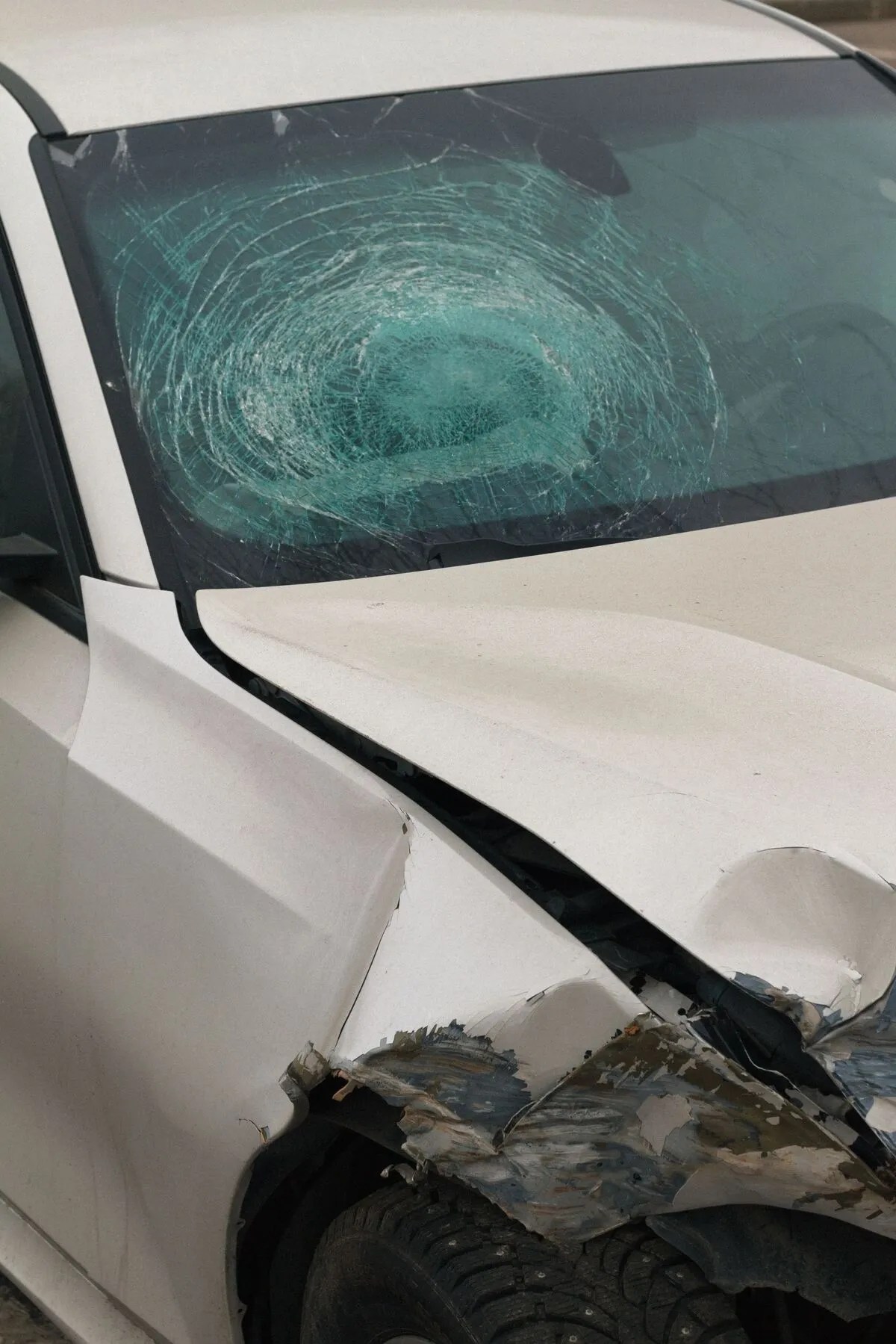Damaged White Car With A Shattered Windshield And Crumpled Front Body After A Collision