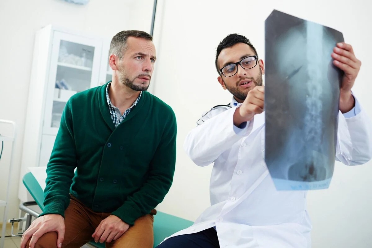 Doctor Showing A Spine X‑Ray To A Patient During An Exam
