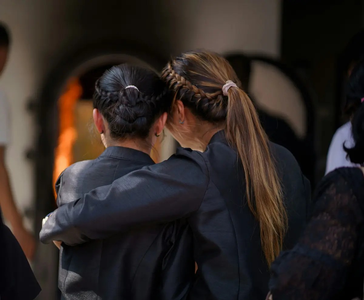 Two People Embracing And Offering Support During A Funeral Or Memorial Gathering
