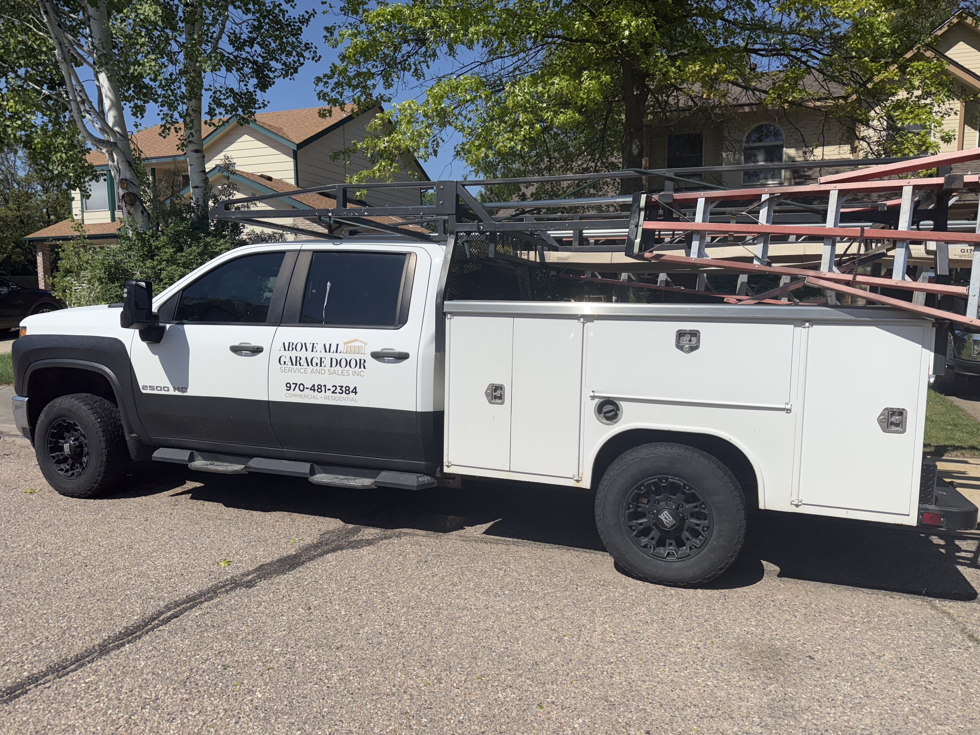 bed, roof-mounted ladder rack carrying equipment, and side door signage for Above All Garage Door Service and Sales, Inc.