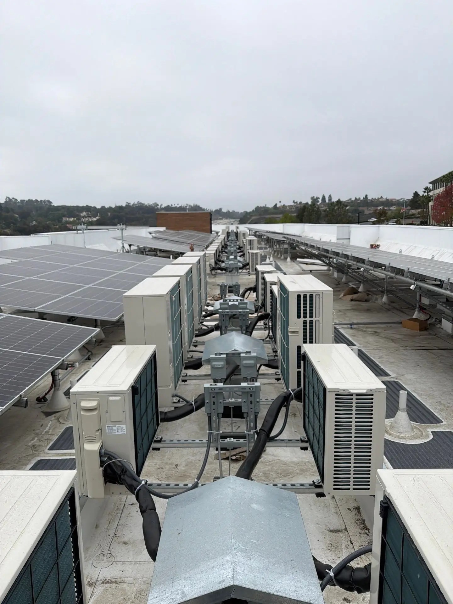 Several HVAC units lined up on a building's rooftop. We conduct Air Balancing tests on HVAC units to ensure the system is working optimally. Verification of HVAC units is also a key part of the ECC/HERS verifications and tests.