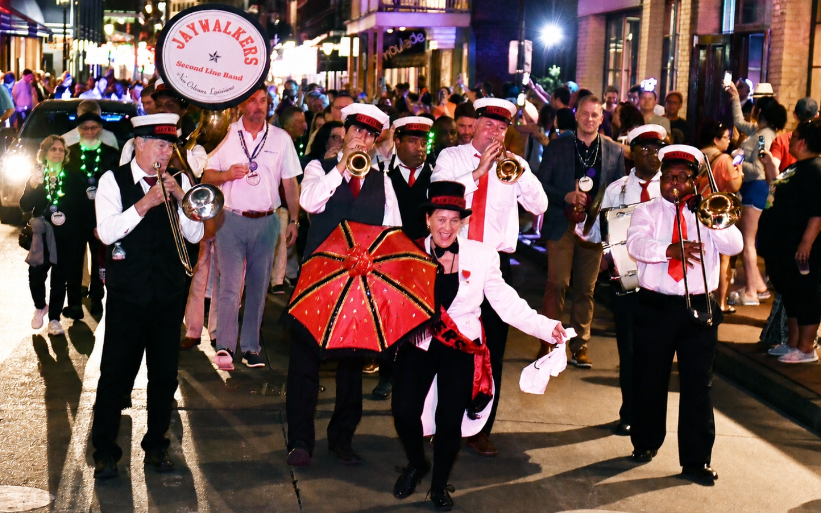 Corporate group joining a second line parade with a brass band in New Orleans.