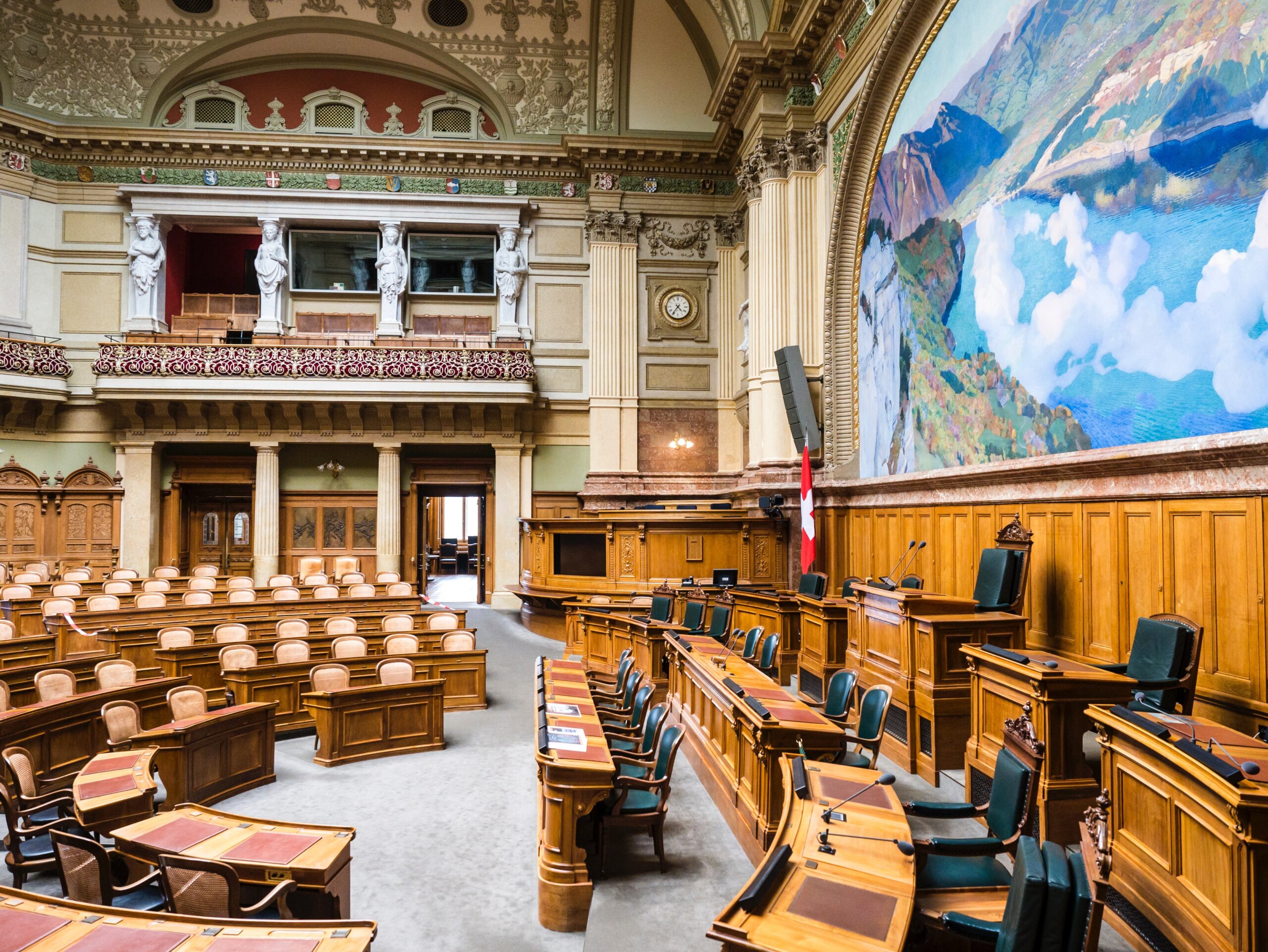 Schweizer Bundeshaus von innen. Tische und Stühle, ein Landschaftsbild an der Wand.