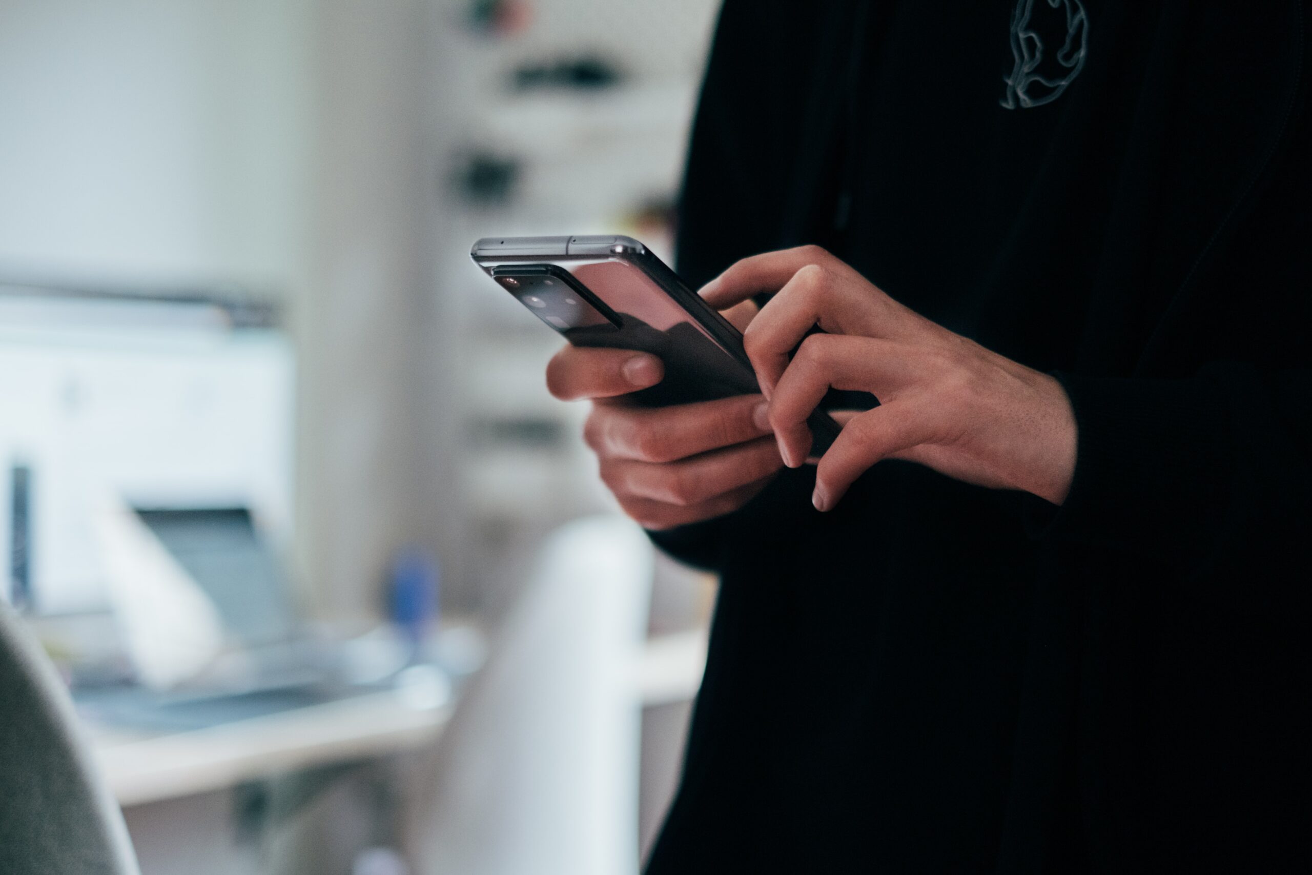 Person hält Smartphone in der Hand und hält den Zeigefinger auf dem Bildschirm.