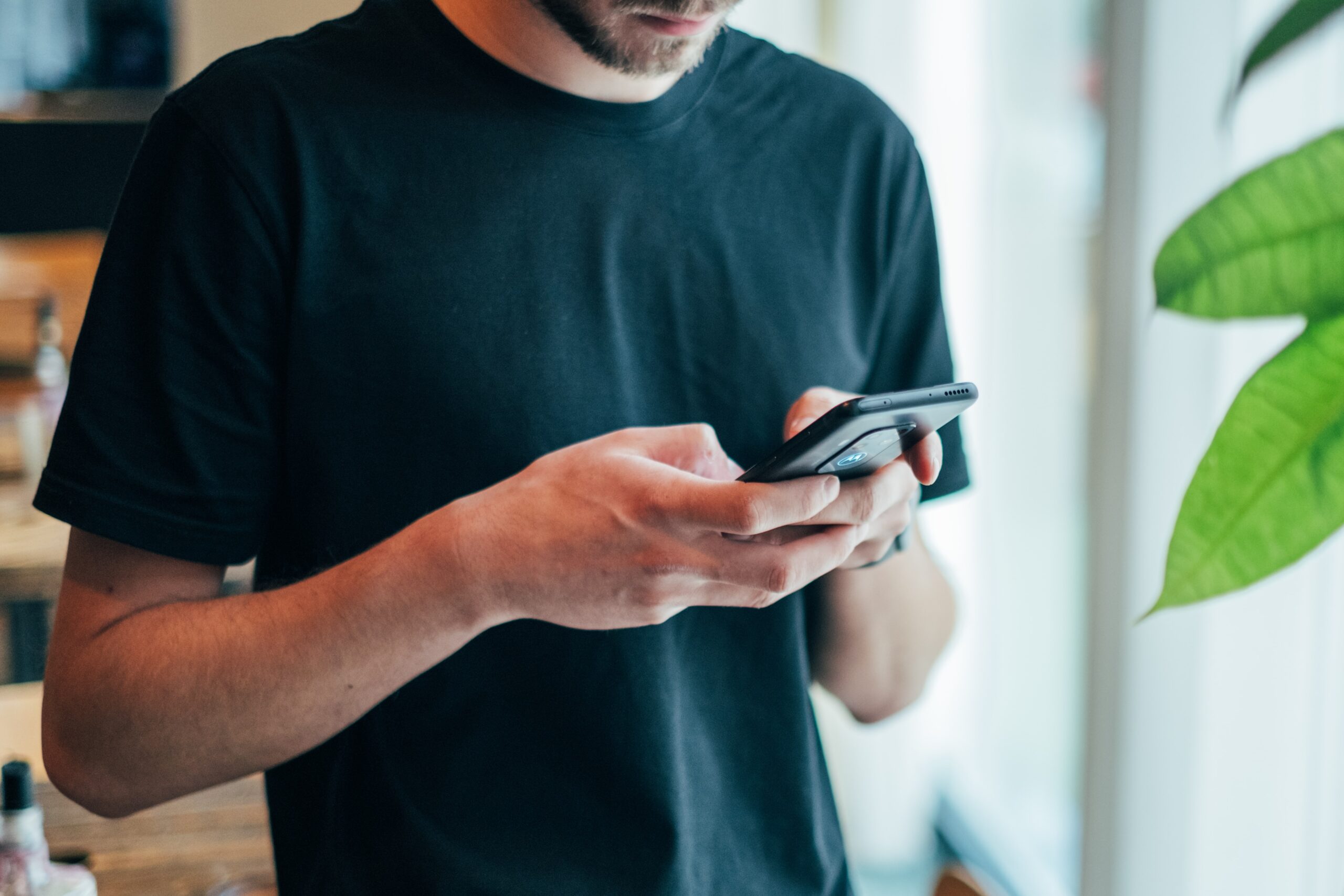 Ein Mann hält ein Smartphone in den Händen, die Daumen sind auf dem Bildschirm.