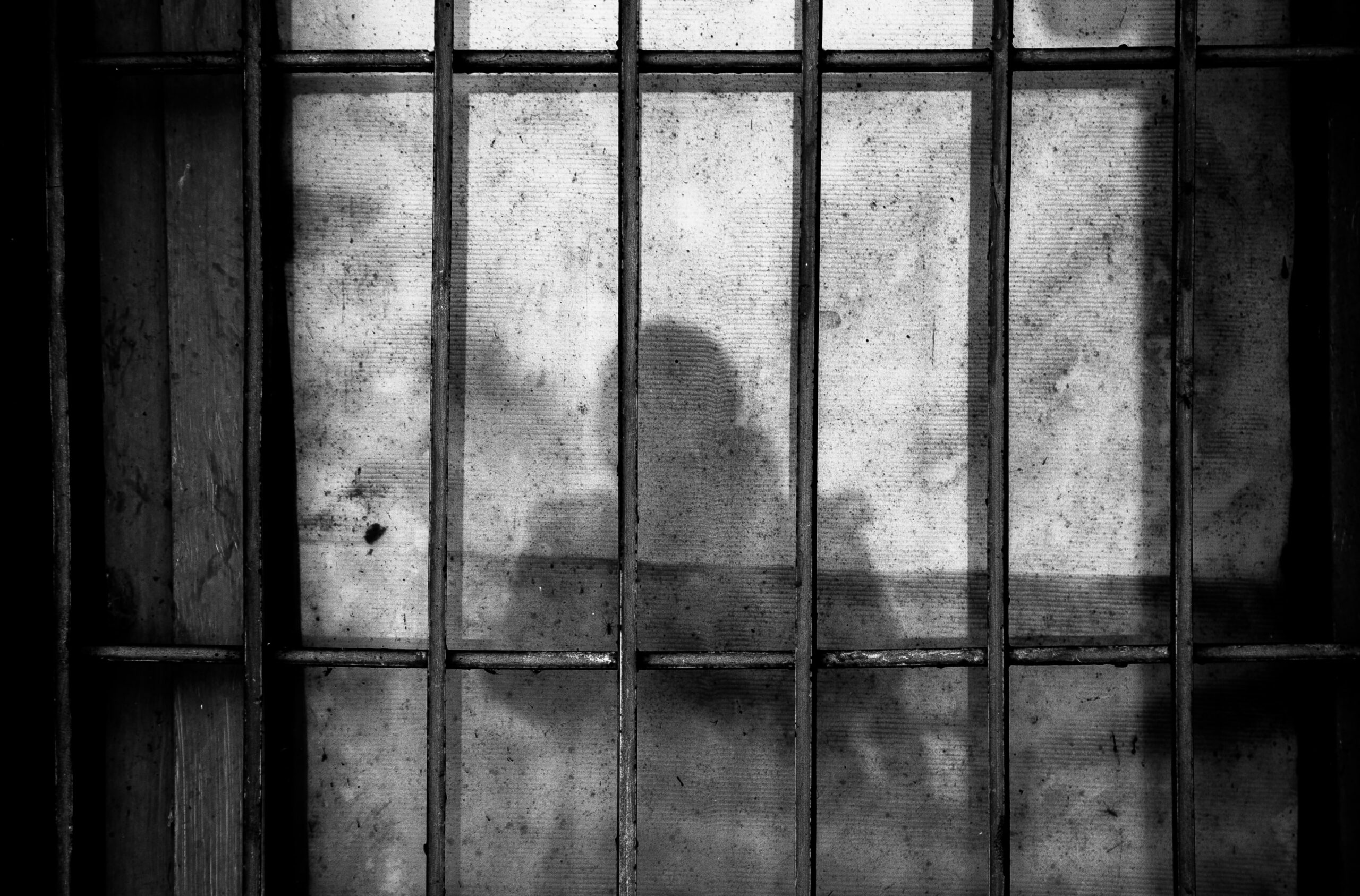 Gitterstäbe, dahinter der Schatten einer Person
