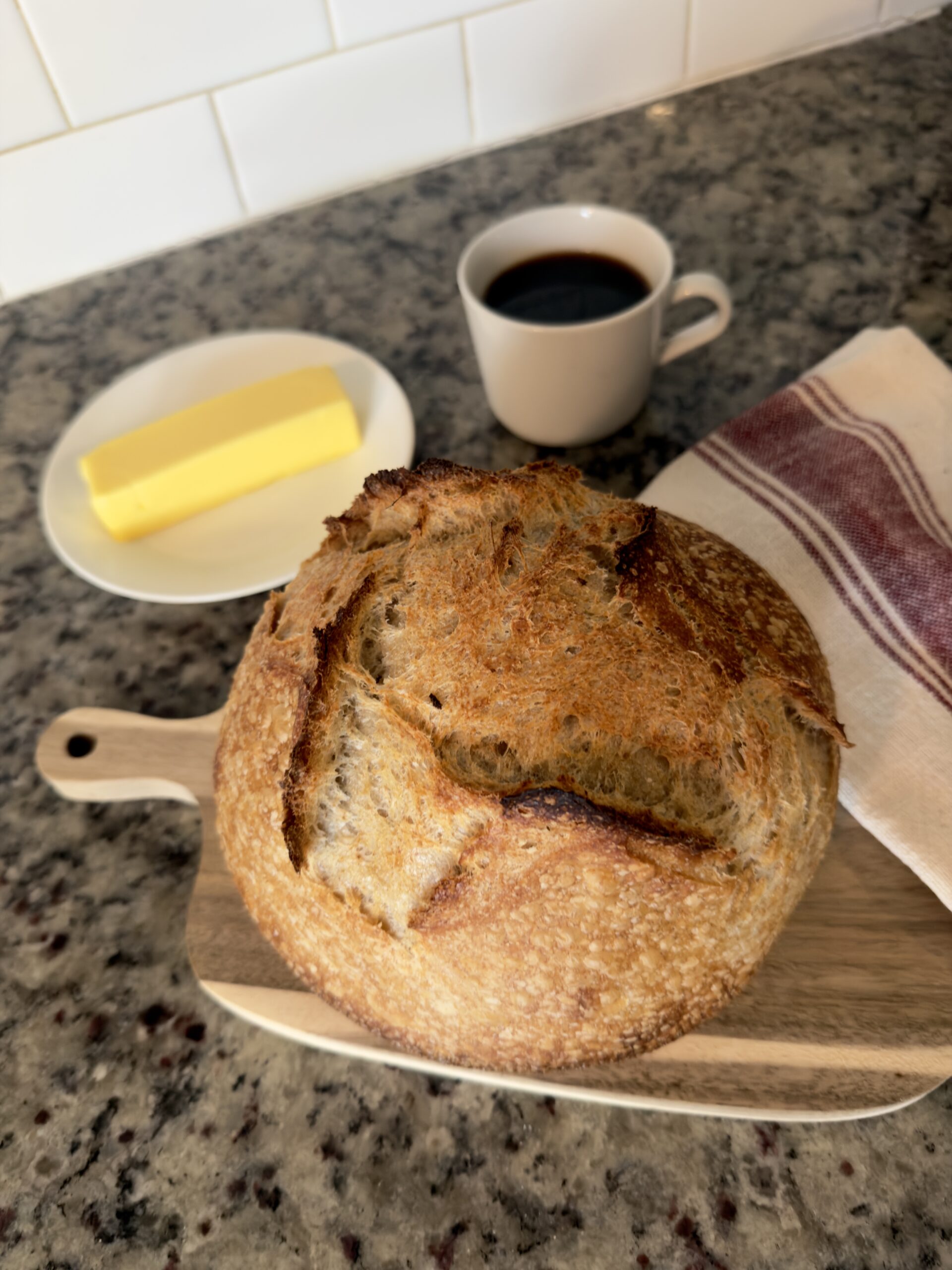 Fresh sourdough Loaf, stick of butter, cup of black coffee.
