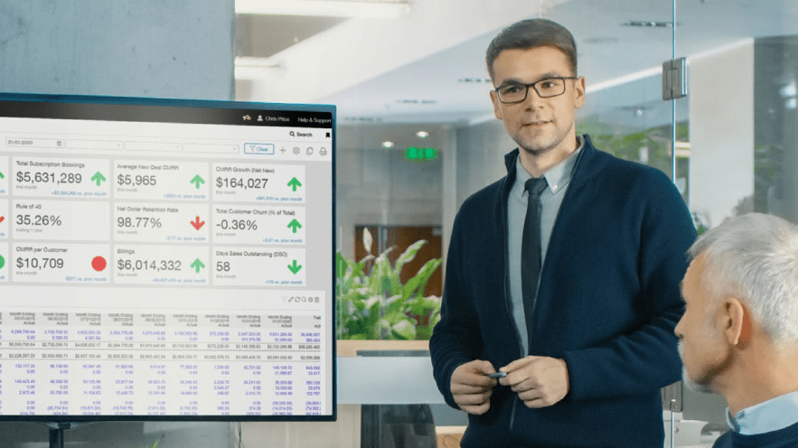 An office worker preenting a Sage Intacct Dashboard to a colleague in a meeting room