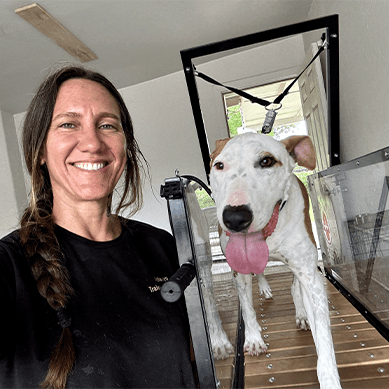 Woman smiling with a dog on a treadmill.