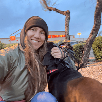 A woman smiling with her dog outdoors.
