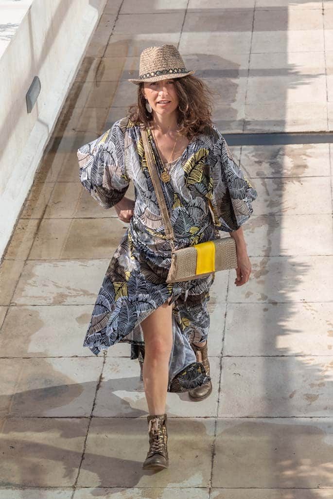 Jeune femme montant dynamiquement les escalier, portant une pochette bandoulière beige et jaune