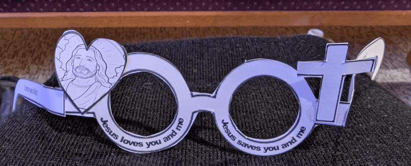 Paper glasses with a heart and a cross, featuring the phrases 'Jesus loves you and me' and 'Jesus saves you and me'.