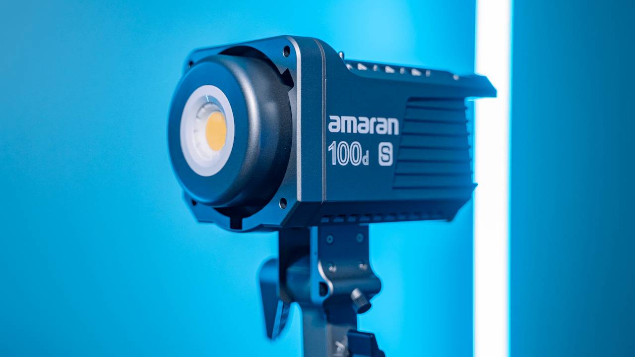 Studio light labeled 'amaran 100d S' mounted on a stand with a blue background.