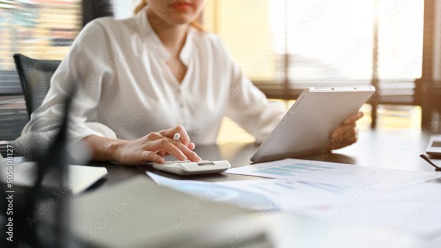 Female accountant using a calculator, checking and calculating a sales accounts