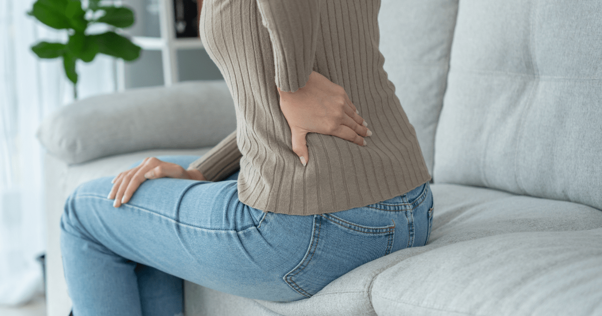 picture of woman hold her back - prepared to attend her first pain reprocessing therapy session in portland oregon