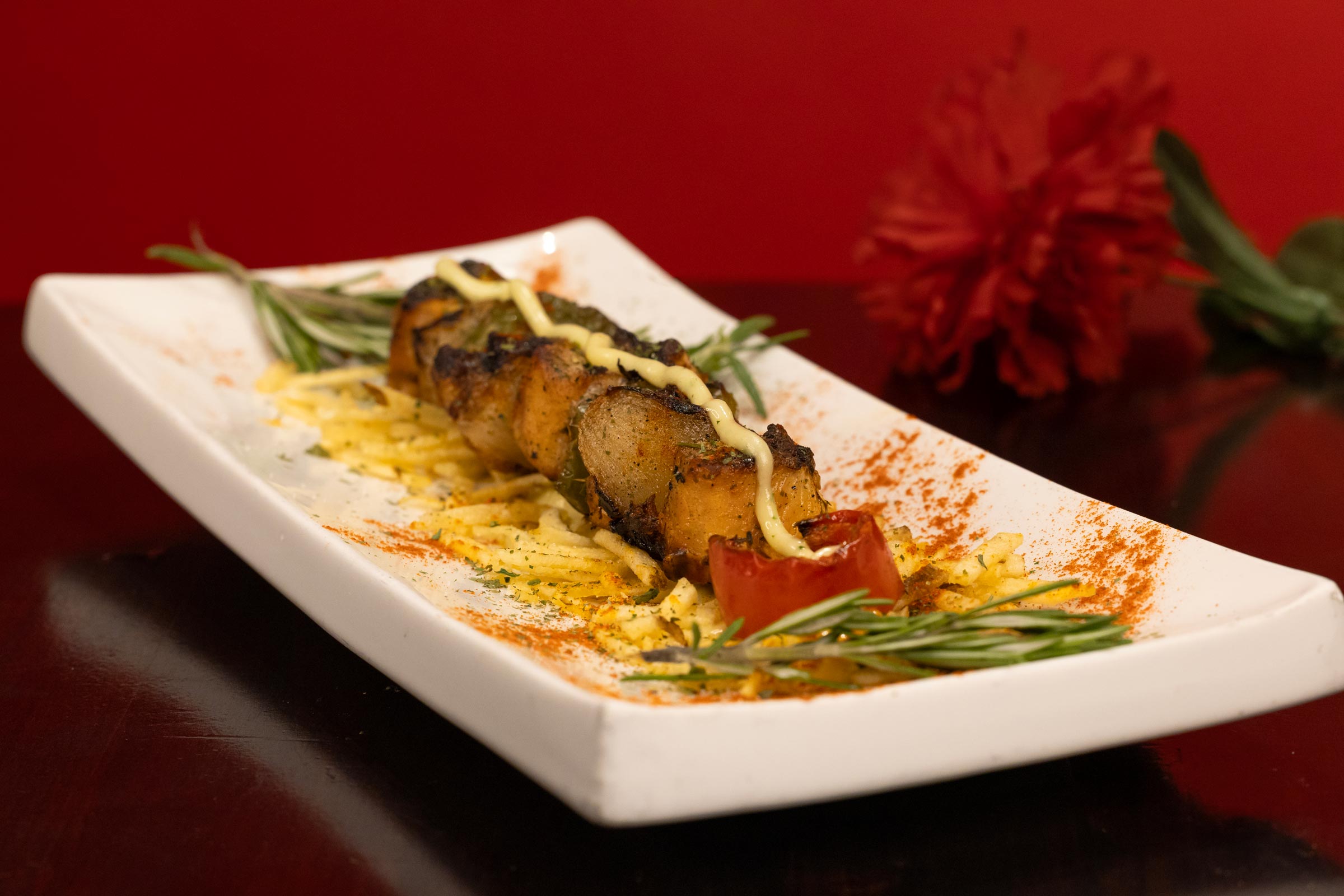Grilled fish tapa with a mayonnaise drizzle and paprika.