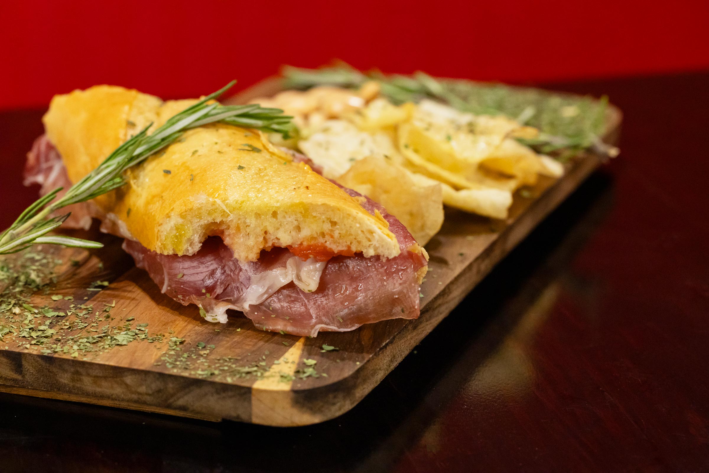 Spanish ham sandwich with chips on a wooden board.